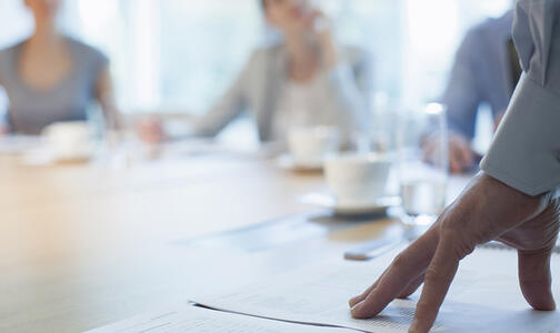 hand on conference table over plans Thumbnail